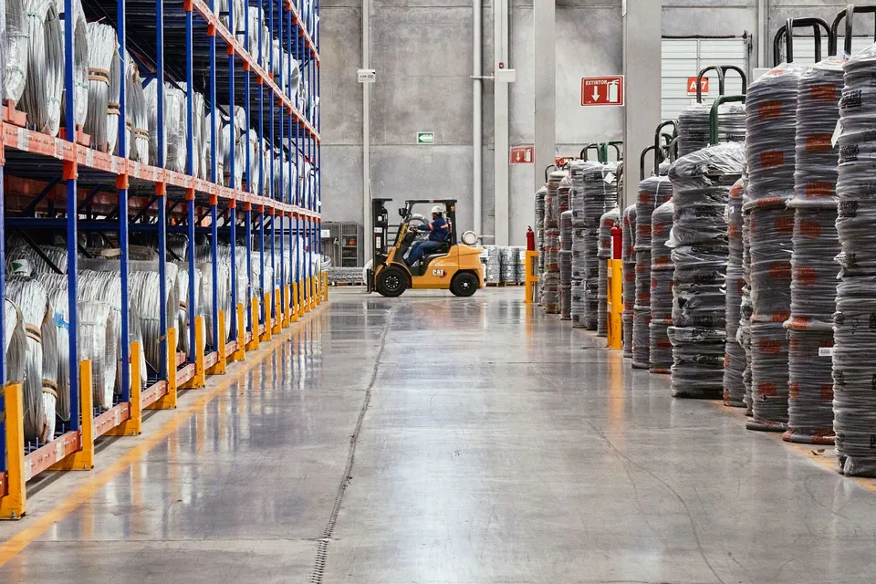 A forklift operates in an industrial warehouse with stacked goods. Efficient distribution setting.
