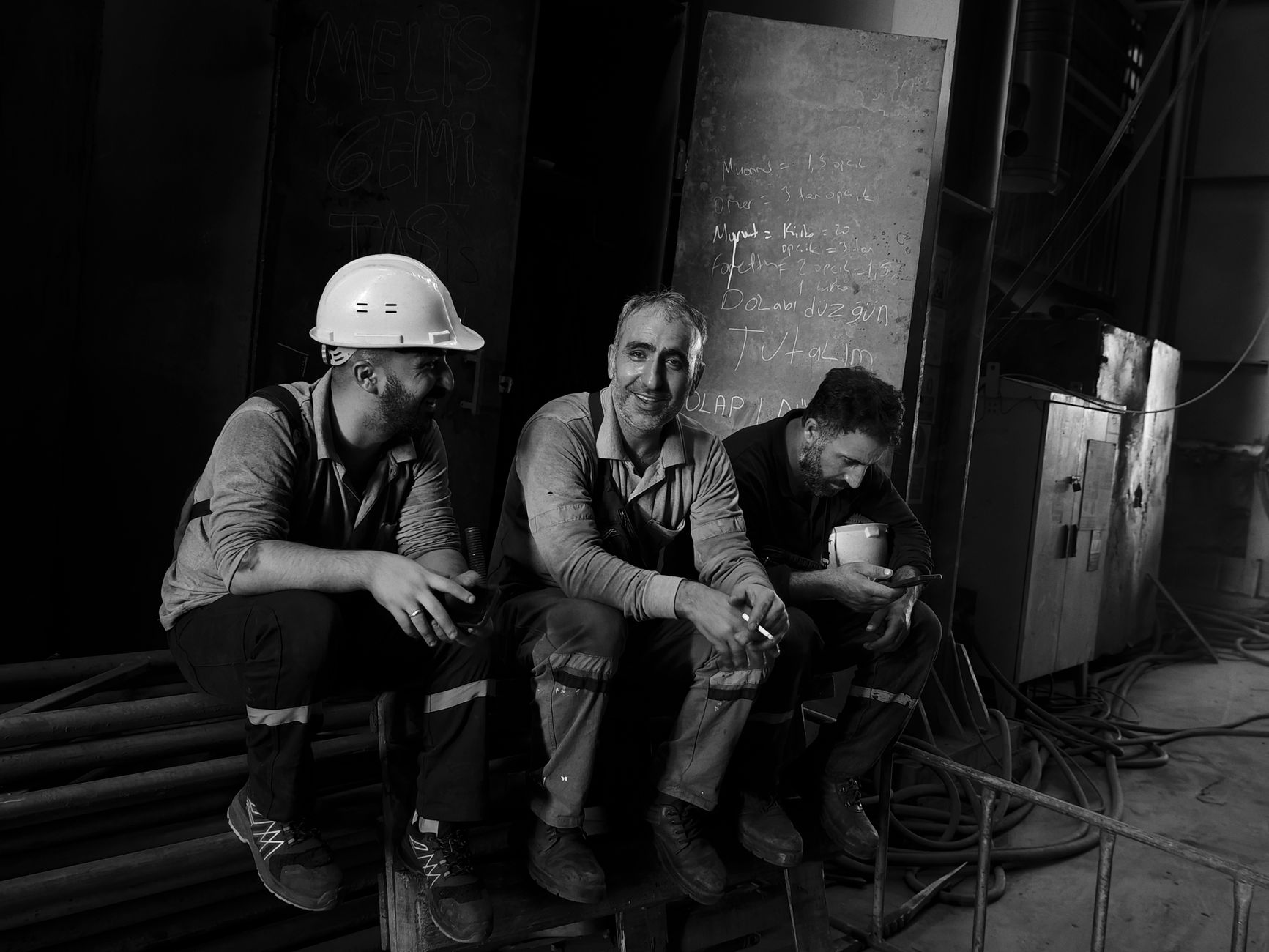 Three male workers in a factory taking a break, showcasing camaraderie and hard work.
